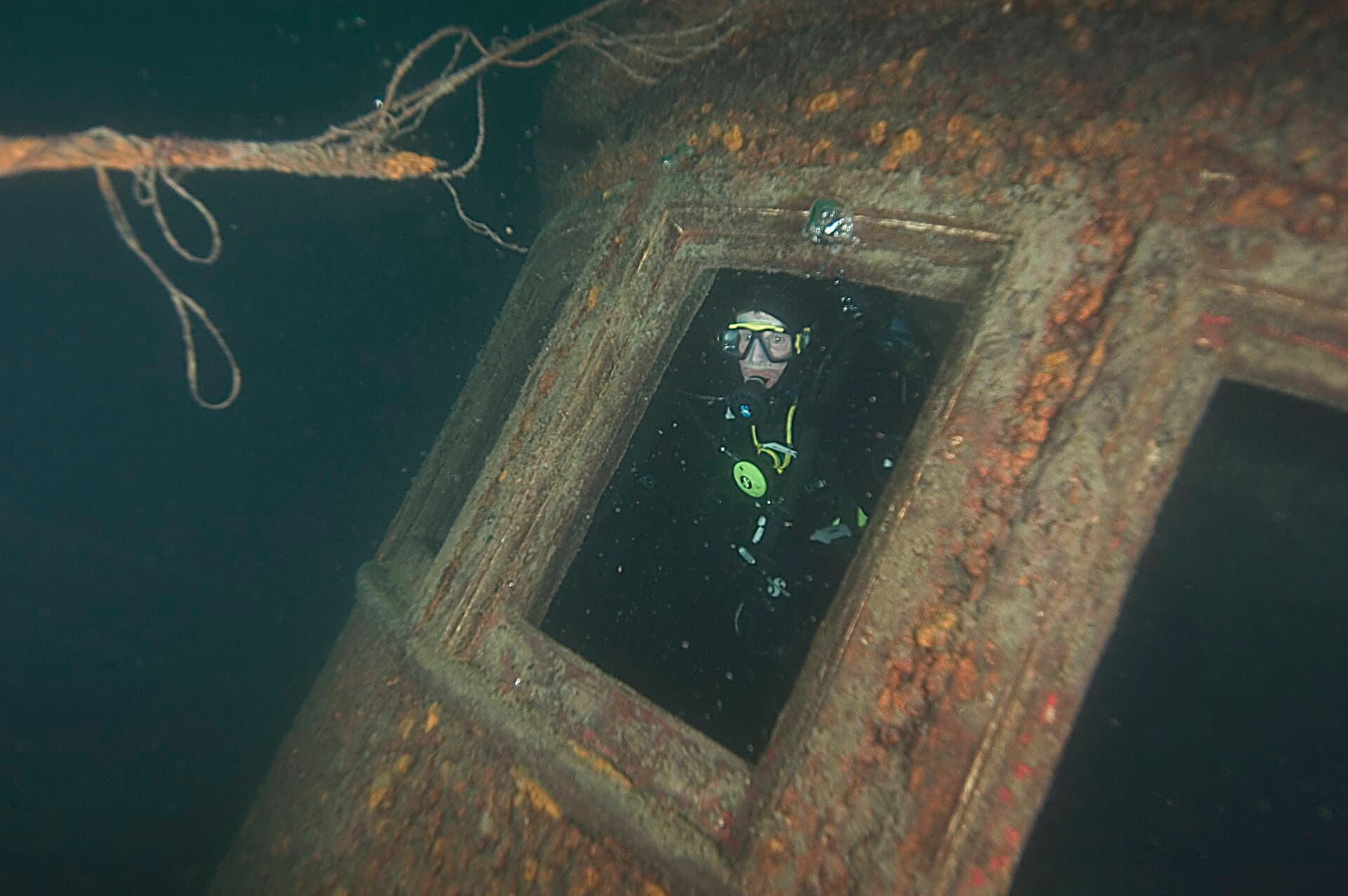 A diver looks out through a window frame inside the wreck of the Chester A. Congdon